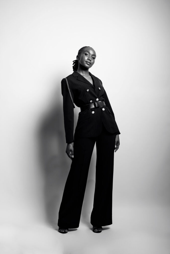 Full length black and white studio portrait of a woman in a tailored black suit