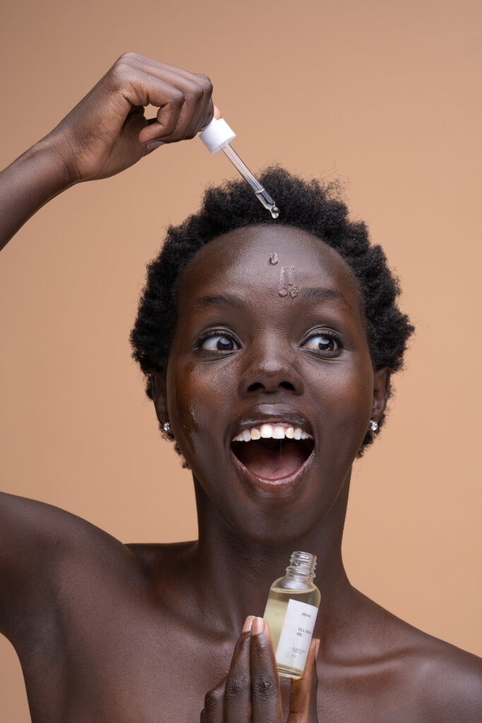 Beauty portrait of a laughing woman applying facial oil with a dropper