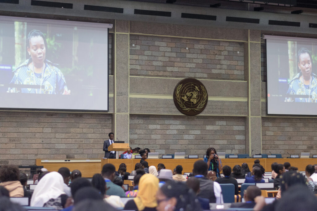 Speaker addressing a full conference hall at a United Nations venue