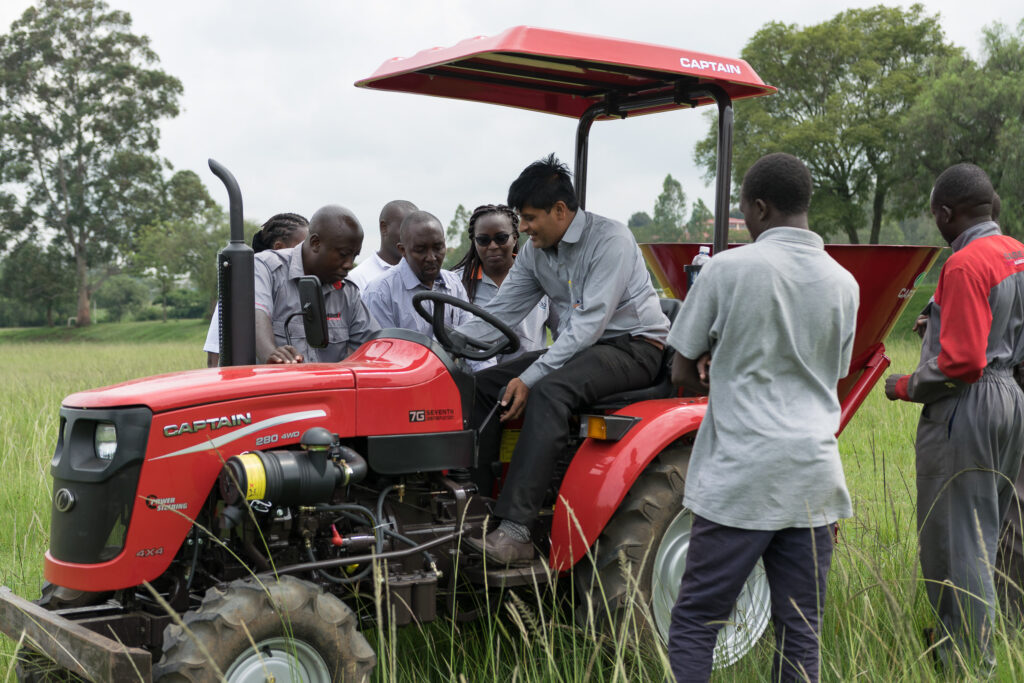 Group gathered around a red tractor during a field demonstration