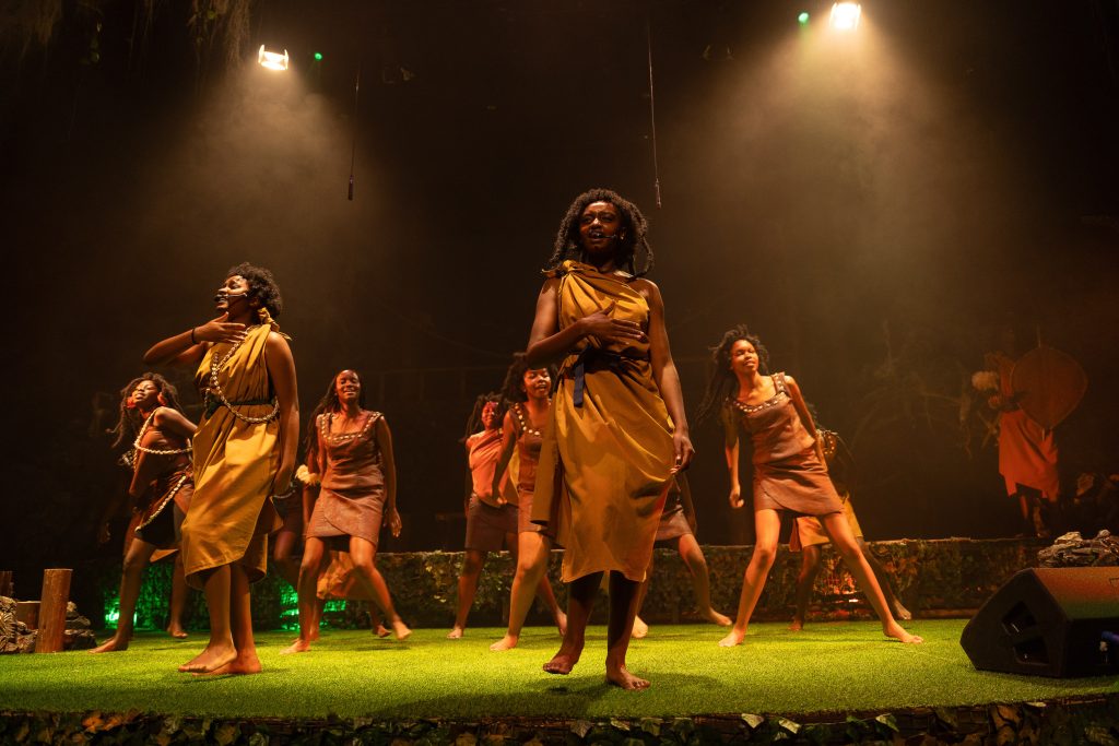 Dancers in gold costumes performing on a lit stage