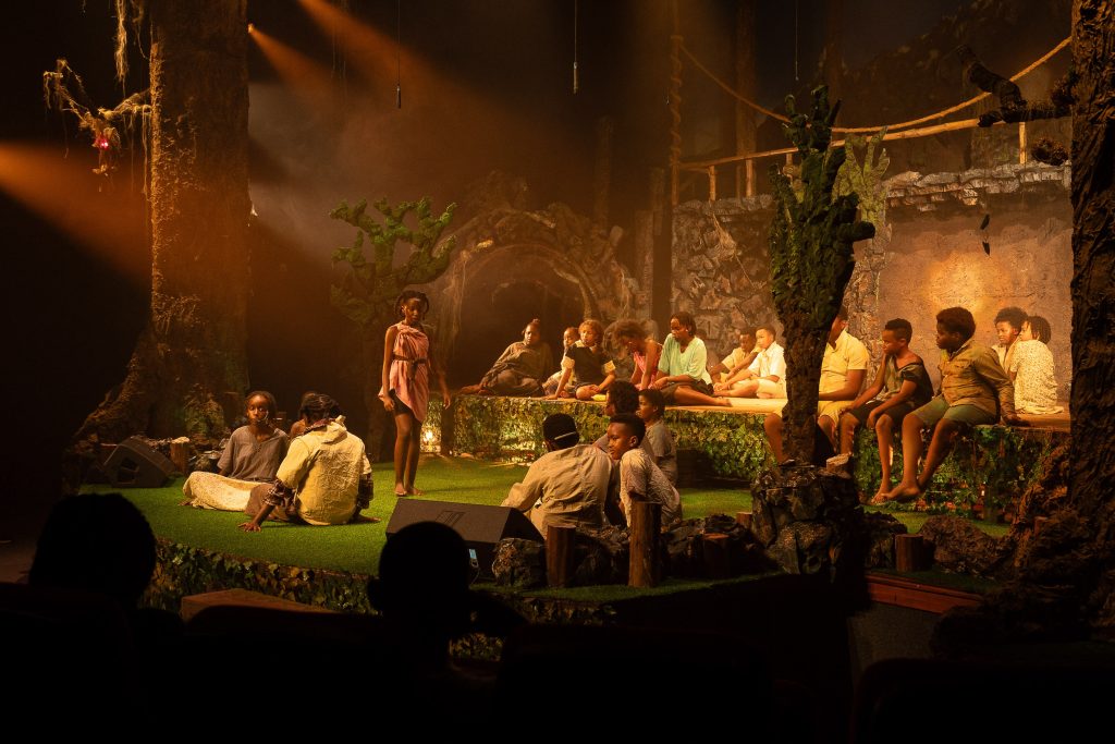 Cast performing a theatre production under warm stage lighting